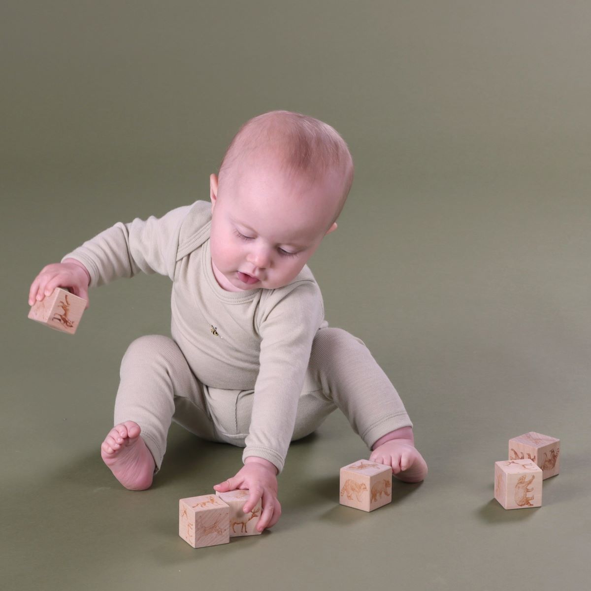 Baby playing wearing Cosy Dreams tea green merino leggings paired with body suit from Dimples New Zealand