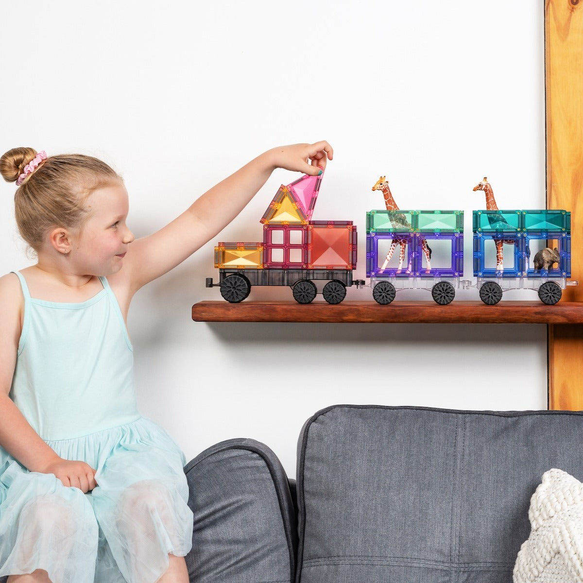 Baby girl playing with animal cargo train made from connetix pastel magnetic tiles