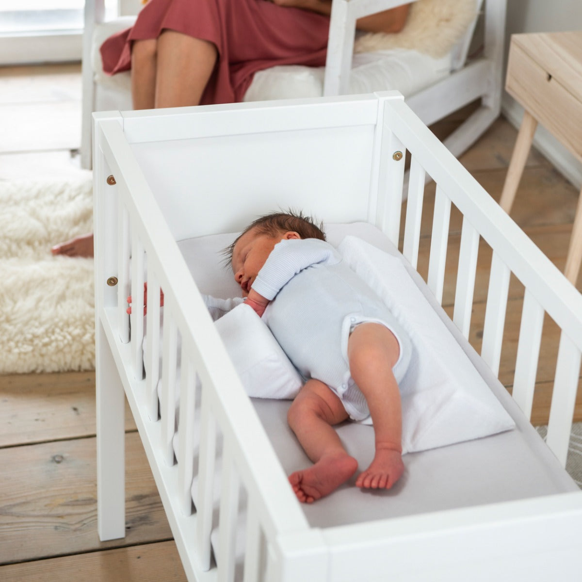 Baby sleeping with Baby positioner in a cot