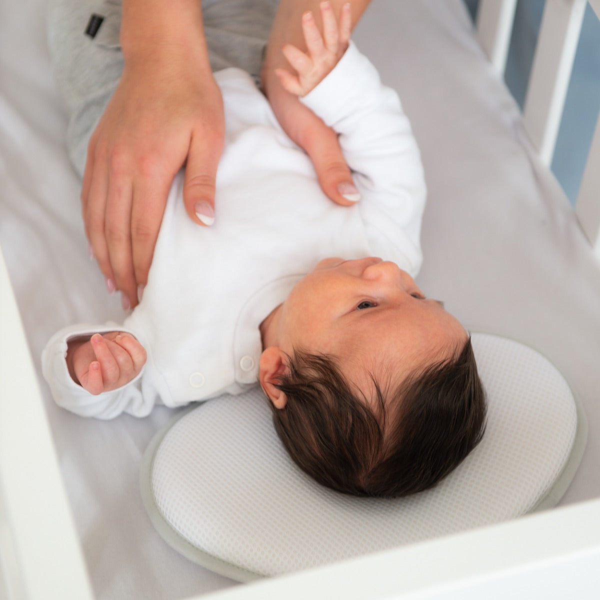 Baby putting boy to sleep in a cot with baby pillow from doomoo