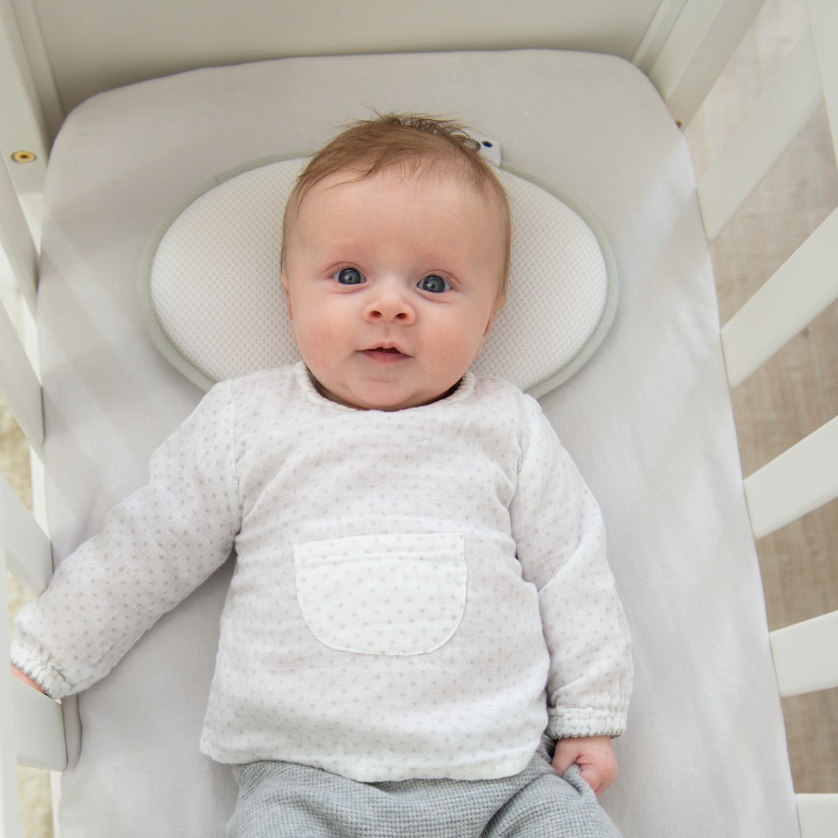 Baby sleeping in a cot with doomoo  baby pillow under the head