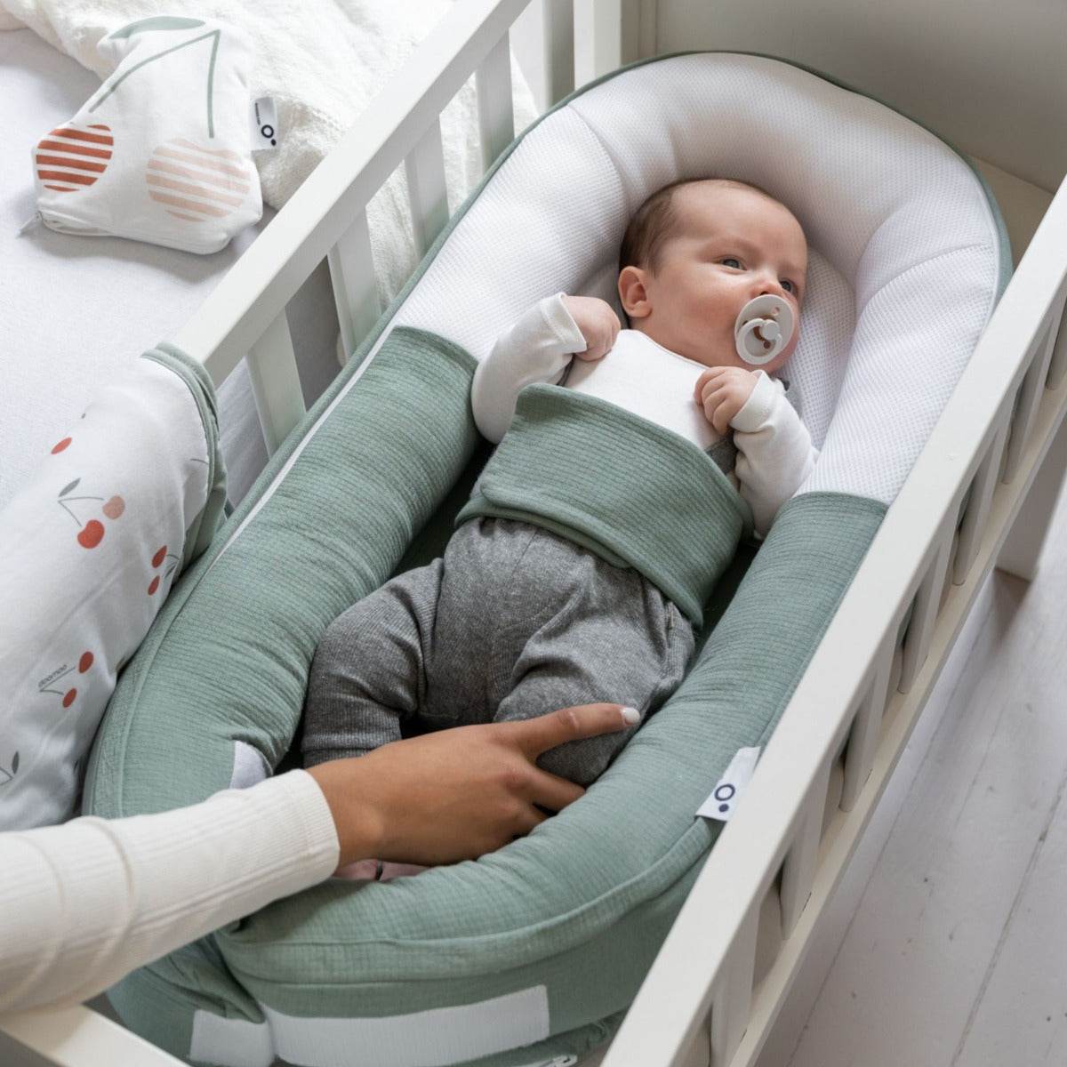 Baby laying in Doo Moo Cocoon nest in Tetra Jersey Green in cot