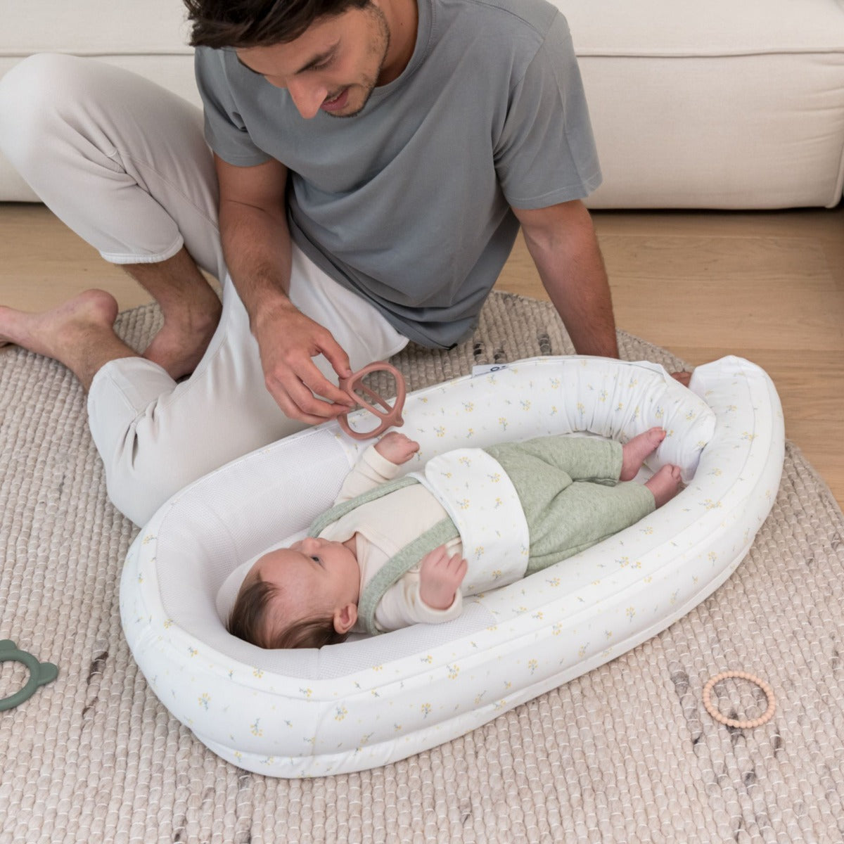 Baby laying in Doo Moo Cocoon nest in Flower Yellow with Father