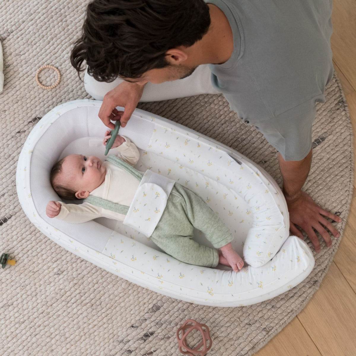 Baby laying in Doo Moo Cocoon nest in Flower Yellow with Father