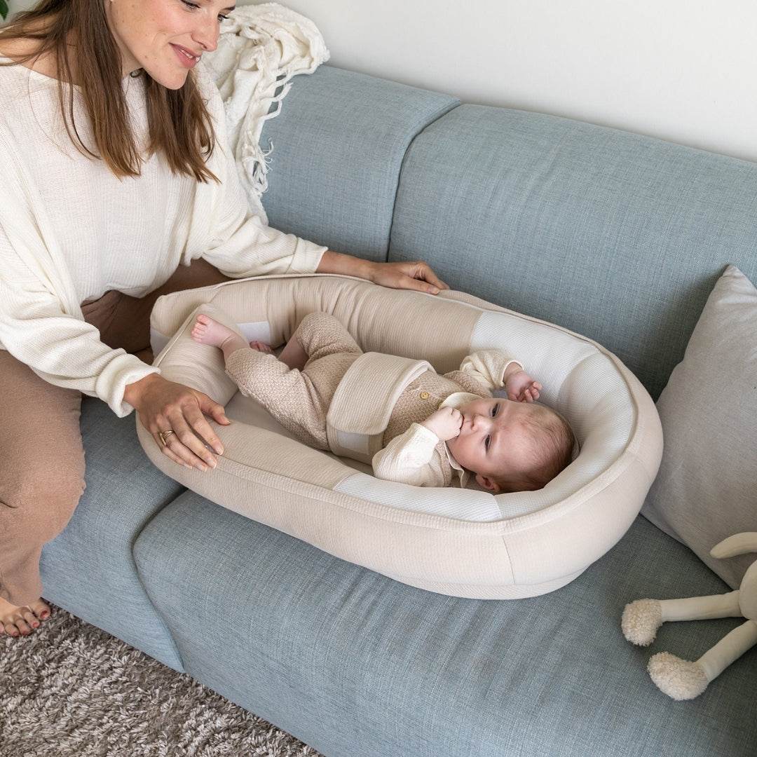 Baby in Baby resting in Doo Moo Cocoon nest in Tetra Jersey Sand with Mother on the couch