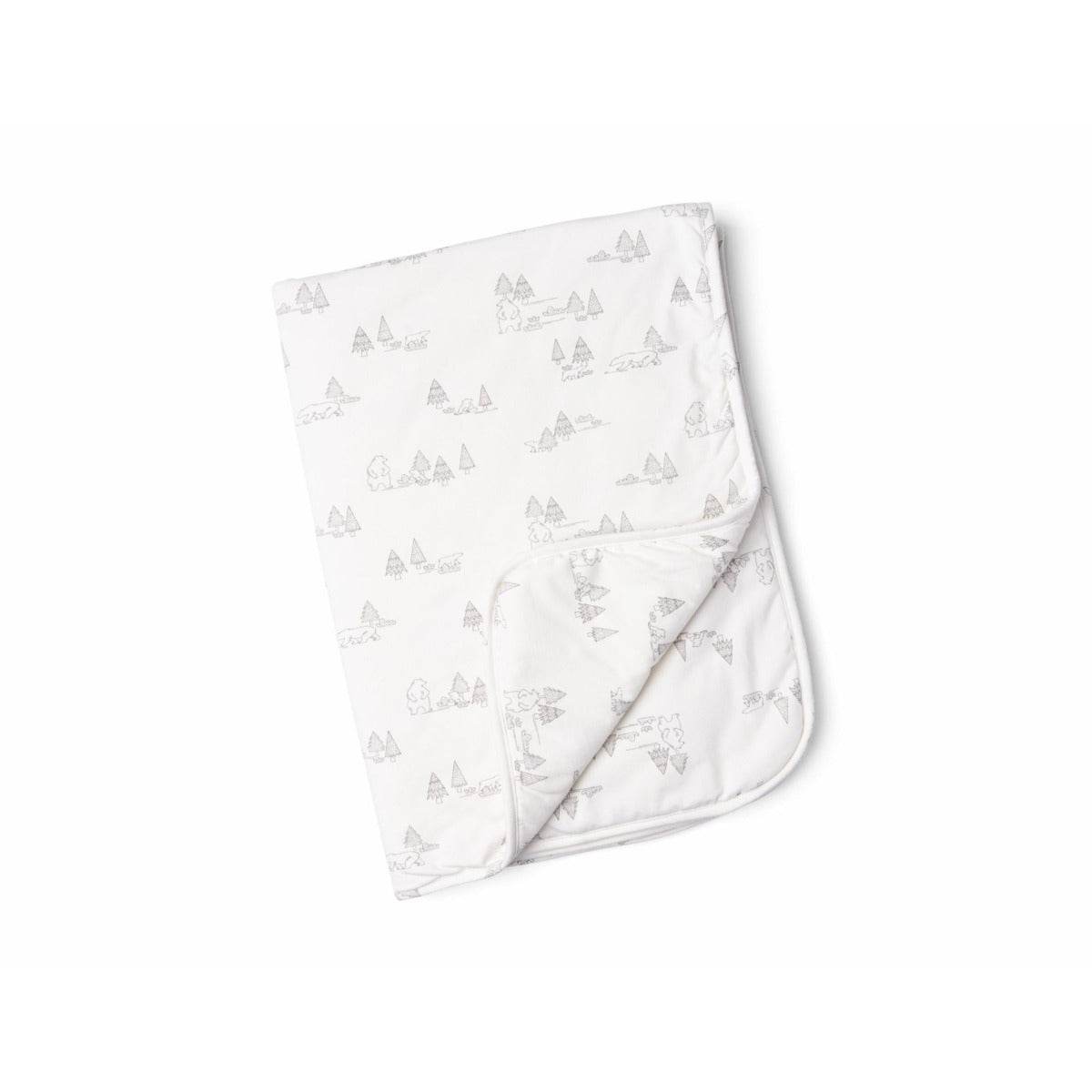 A folded white blanket with a subtle pattern of trees.