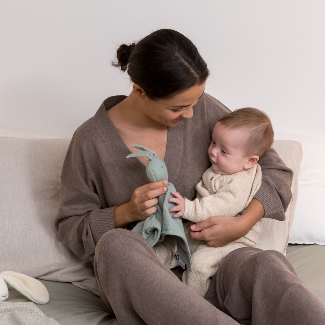 Mother and baby playing with doomoo bunny detachable baby soother in sage green