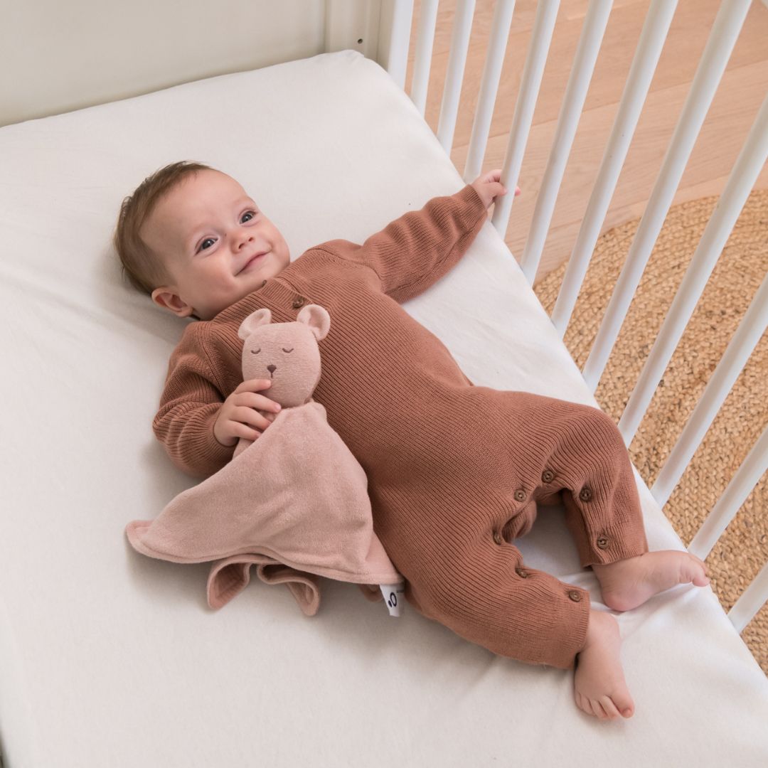 Baby playing in cot with doomoo bunny detachable baby soother in pink