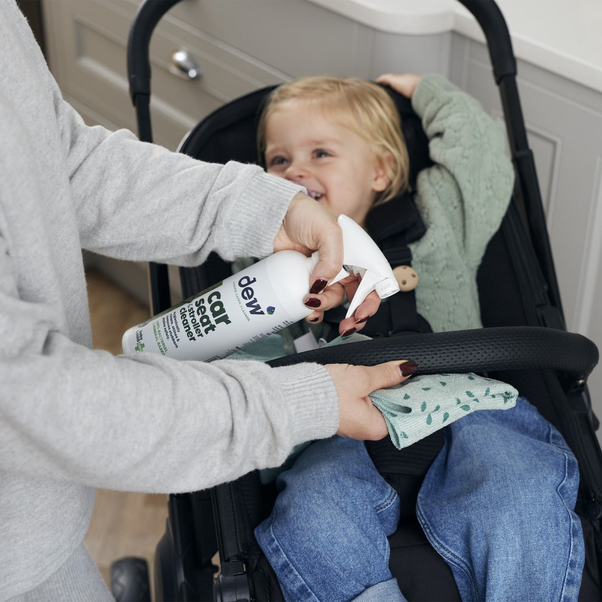 Mother cleaning stroller with car seat and stroller cleaning spray