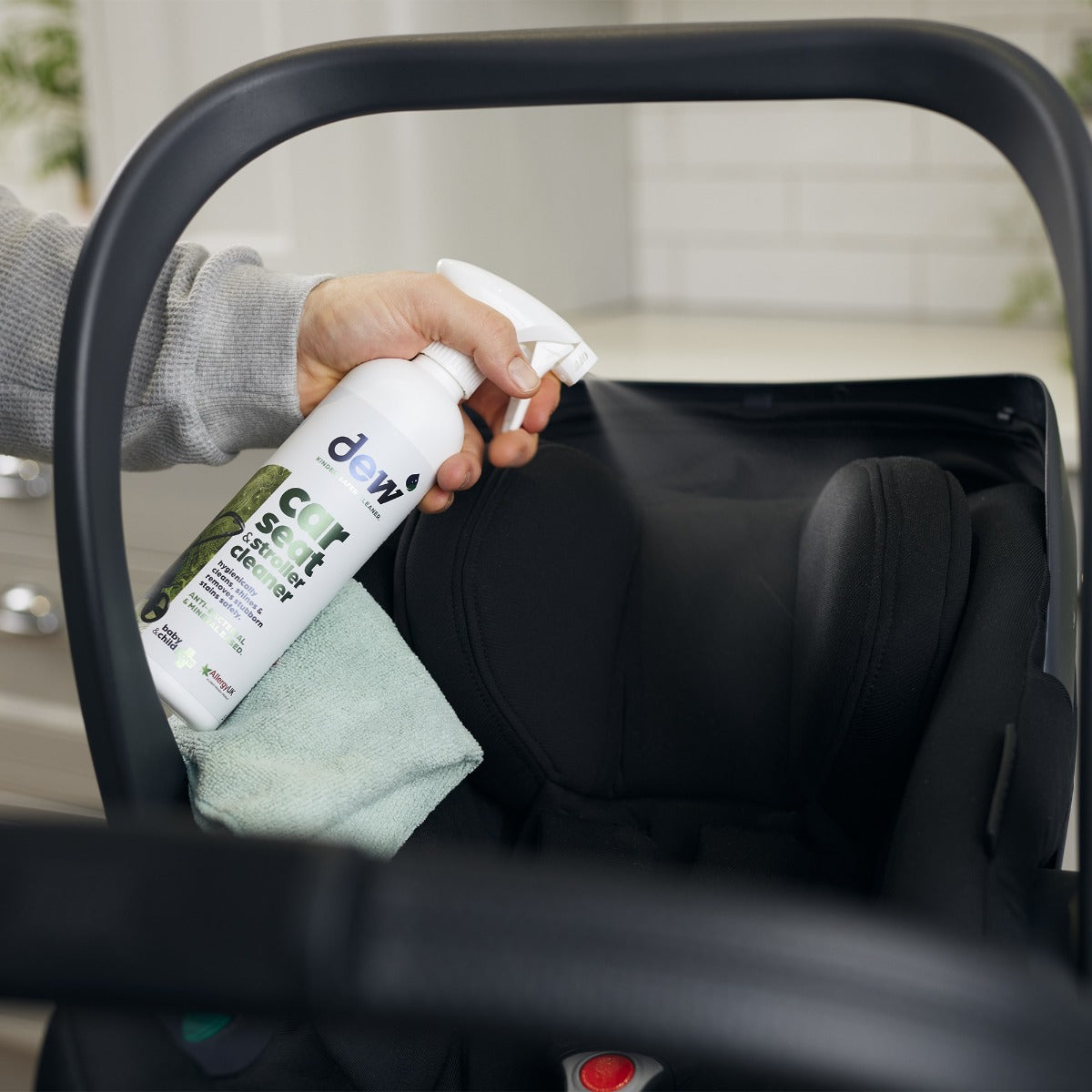 Mother cleaning car seat with car seat and stroller cleaning spray
