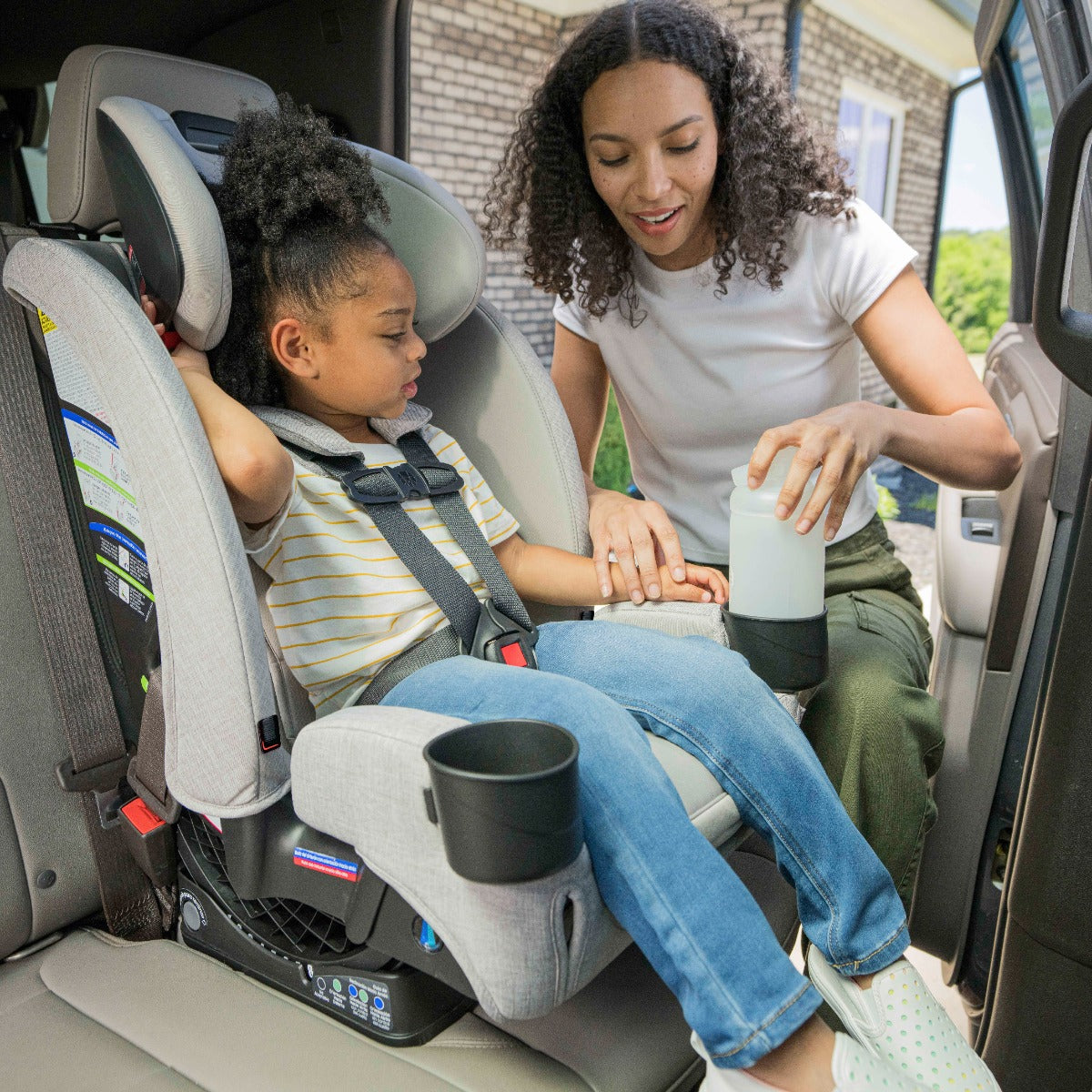 Mother placing baby girl and drink bottle in Mineral Grey One4Life Car Seat side view