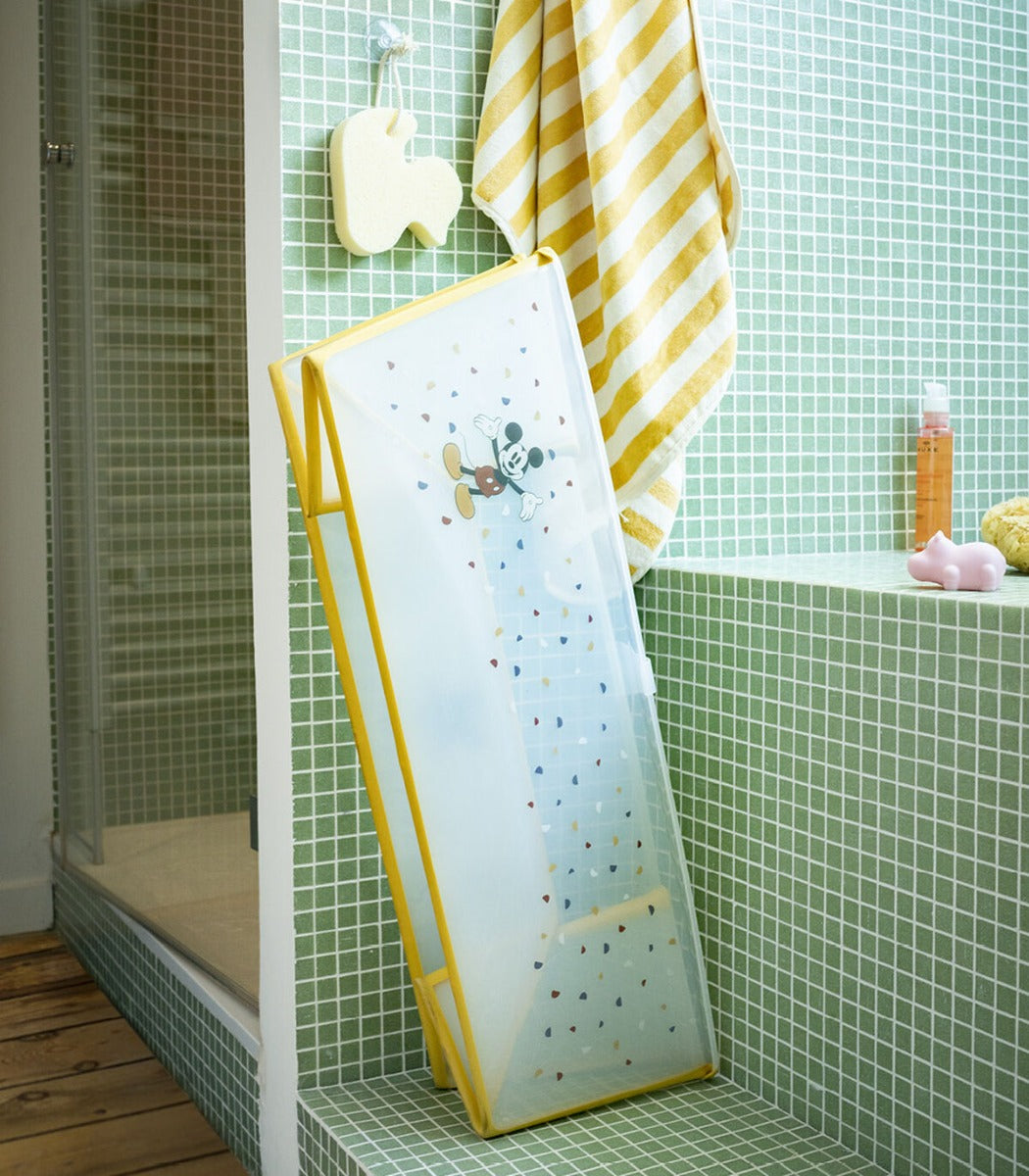 Stokke Flexi Bath in Mickey design leaning against shower