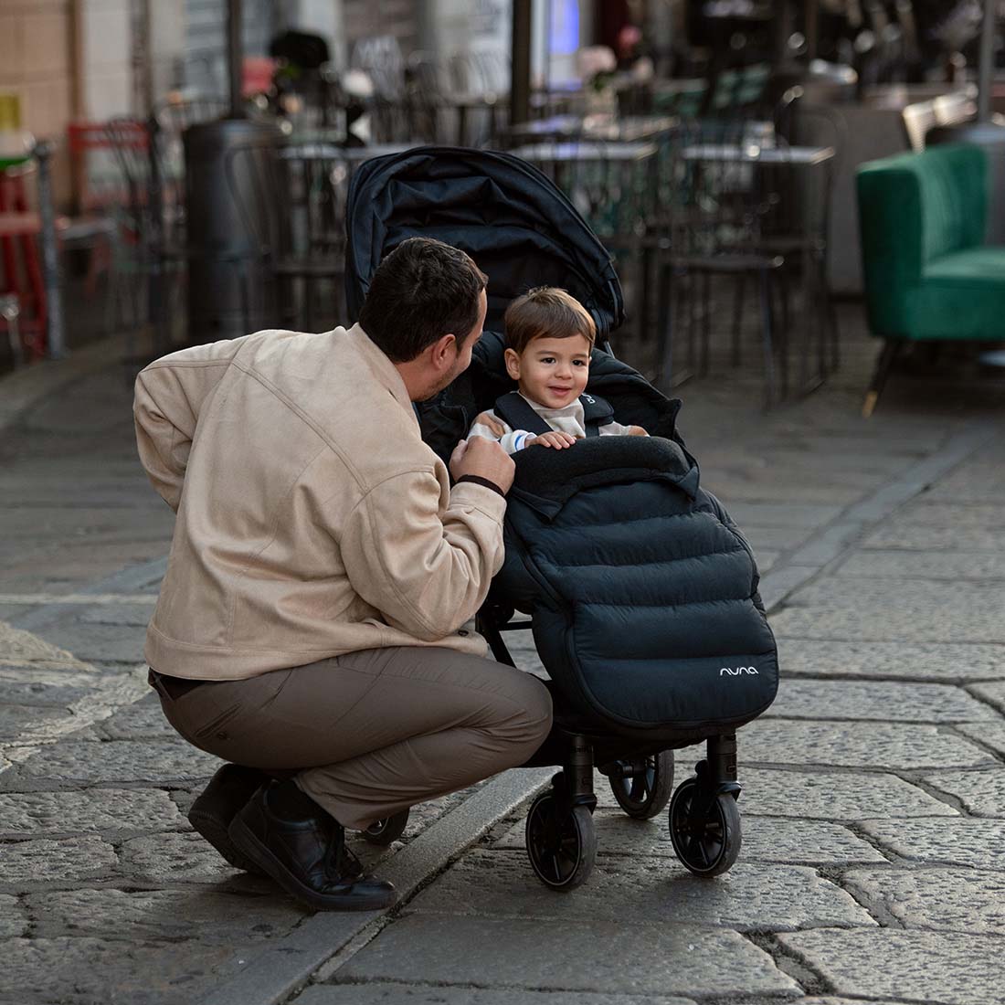 Father on road with kid in a stroller with Nuna winter set footmuff