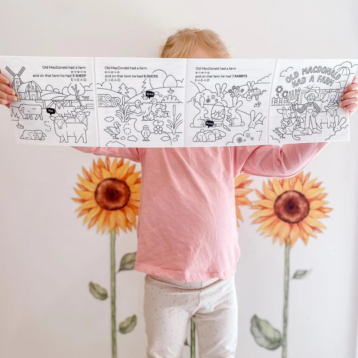 Girl holding HeyDoodle Farm story silicone reusable colouring mat