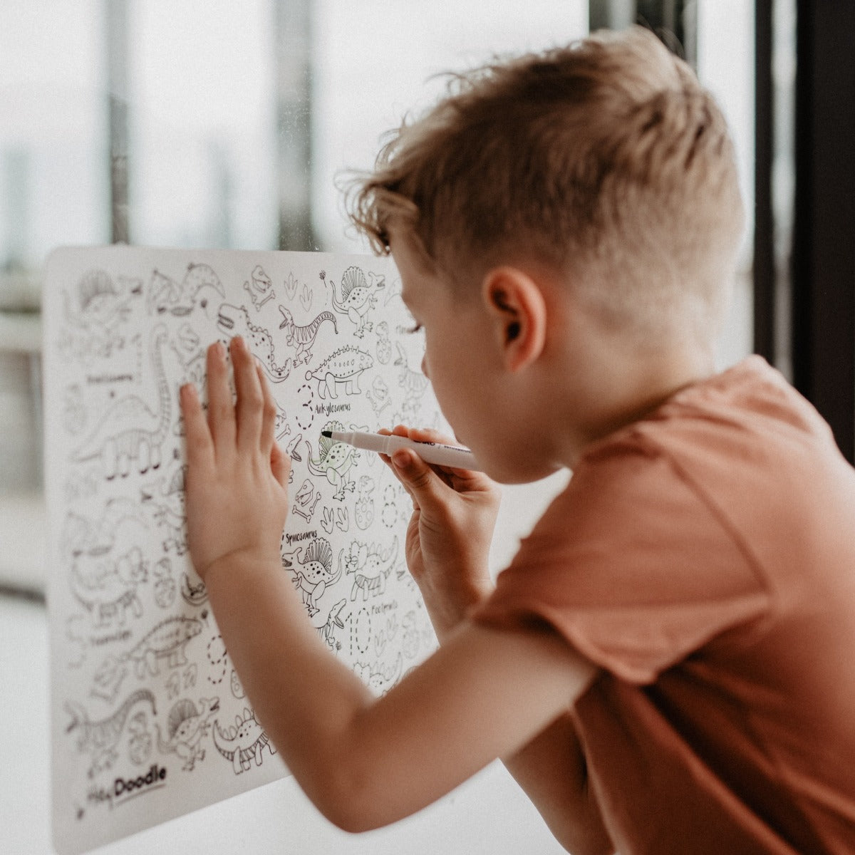 Boy colouring on HeyDoodle reusable silicone doodle activity mat
