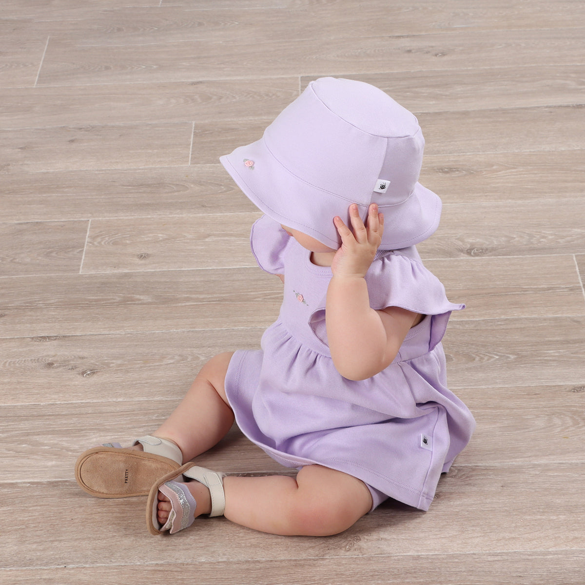 Baby girl playing happily wearing Cotton Sunhat and frill dress in lilac color with rose embroidery 