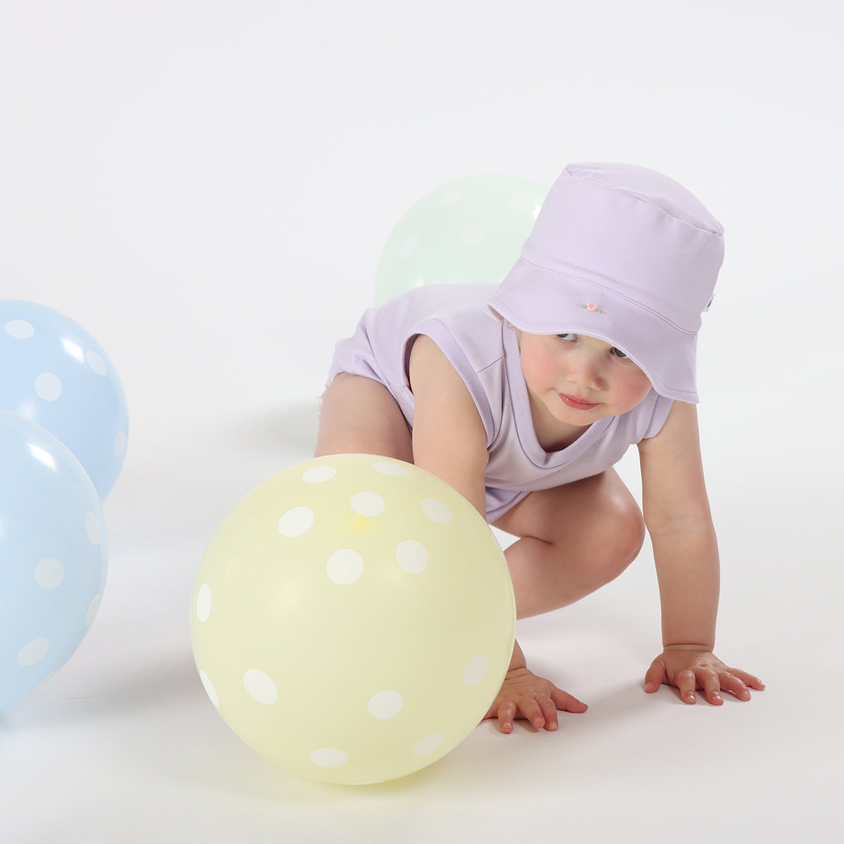 Baby girl playing happily wearing Cotton Sunhat and slouch bodysuit in lilac color with rose embroidery 