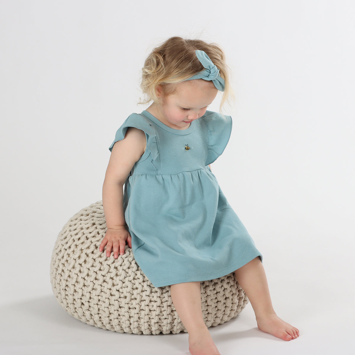 Baby girl wearing Cotton frill dress in ocean and bee embroidery pairing it with tie headband