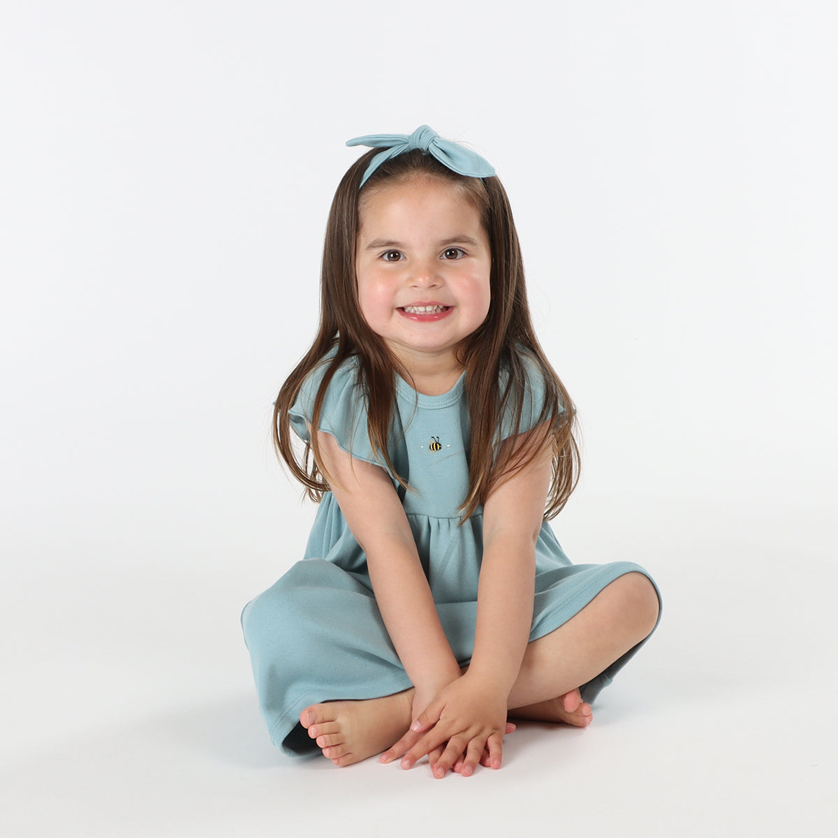 Baby girl wearing Cotton frill dress in ocean and bee embroidery pairing it with tie headband