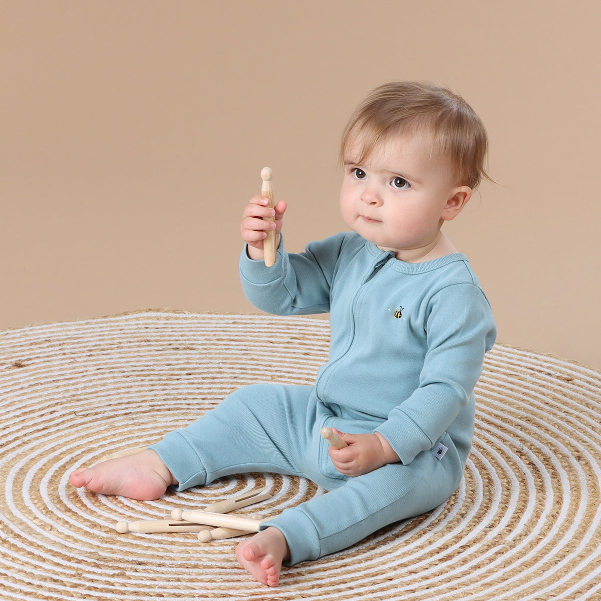 Little girl wearing Cotton Zip long sleeve Babygrow with bee embroidery in ocean color