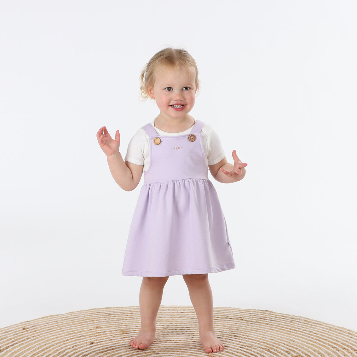 Playful baby girl wearing Cotton Pinafore dress for girls in lilac with rose embroidery