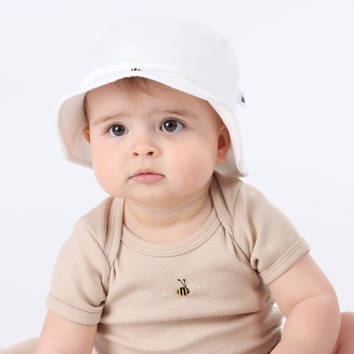 Baby wearing Dimples bodysuit from the Dimples 2024 Fashion Collection in Sand