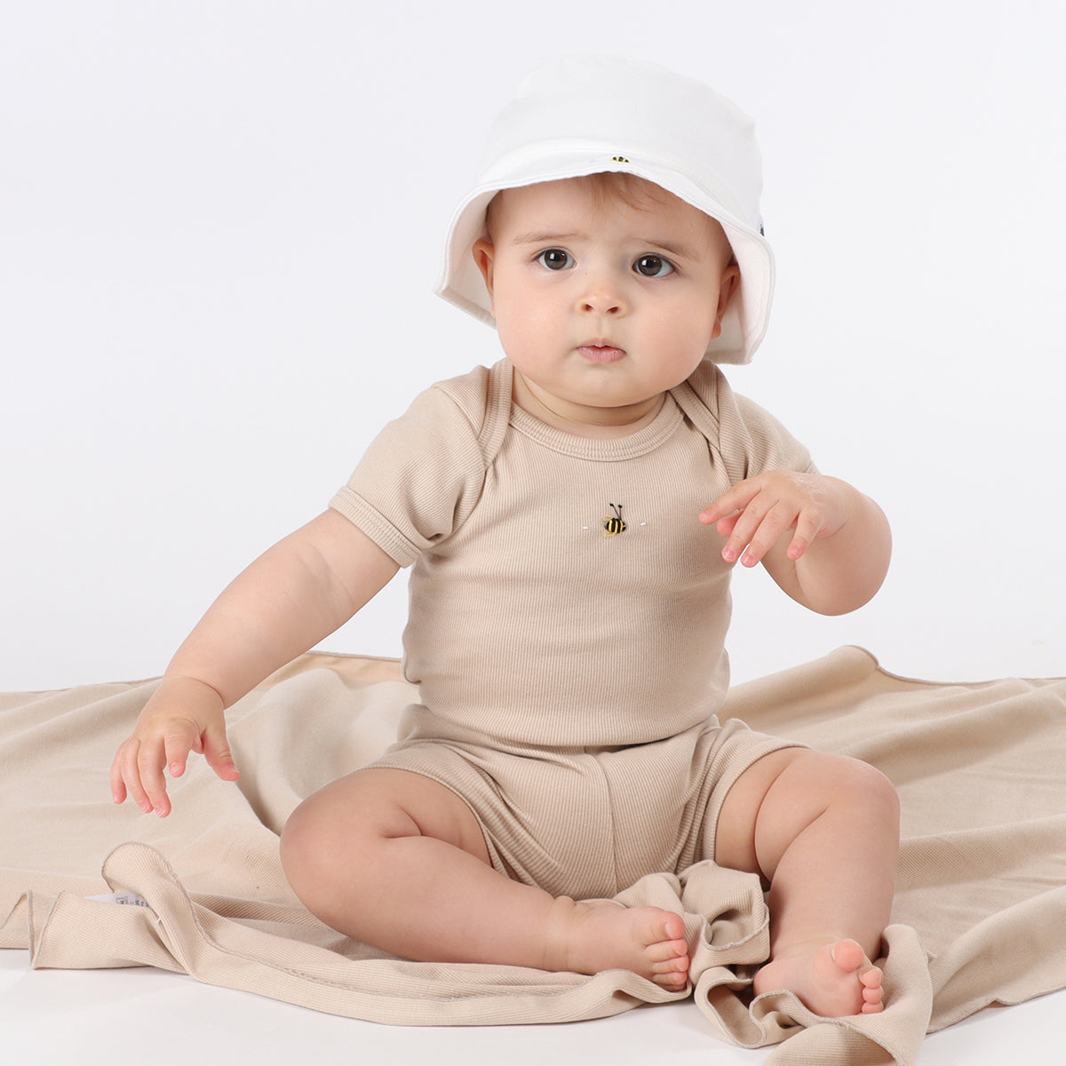 Baby girl sitting on wrap wearing cotton bodysuit and bike shorts