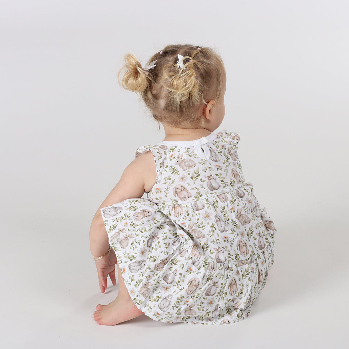 Little girl squatting down, wearing Little bee cotton tiered dress in white with bunny print 