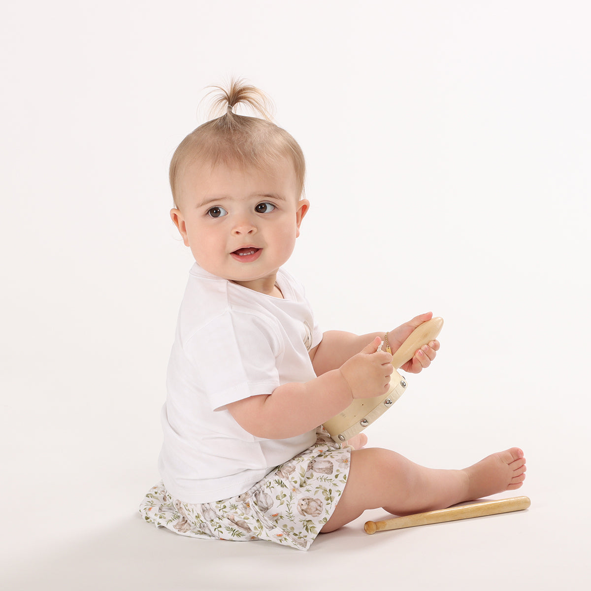 little girl sitting and playing with rattle wearing cotton frill skirt from little bee by dimples with bunny print