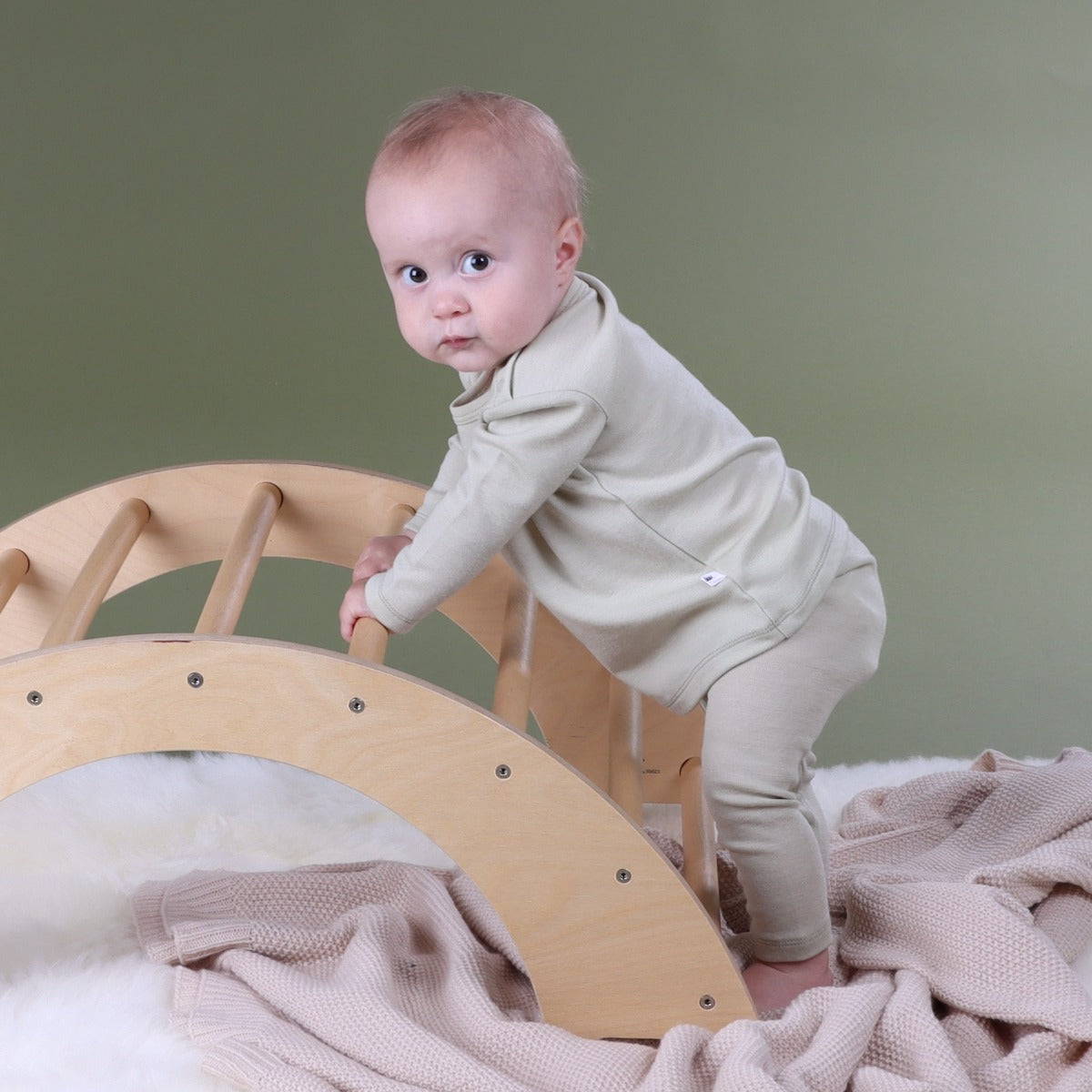 Baby playing wearing Cosy Dreams tea green merino leggings paired with long sleeve top from Dimples New Zealand
