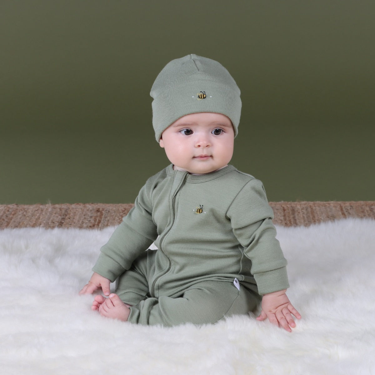 Baby sitting, wearing Arctic Adventure Merino Zip Baby grow and beanie in Moss from dimples in new zealand