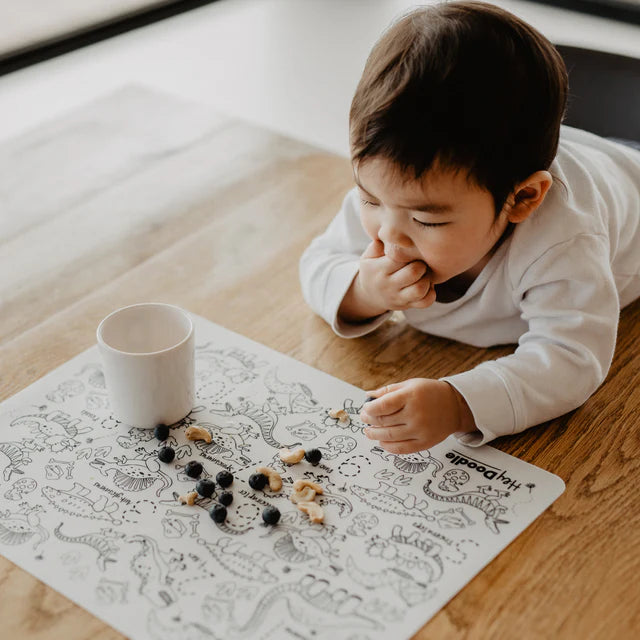 Baby boy eating fruits on HeyDoodle silicone reusable colouring mat with letters and animals