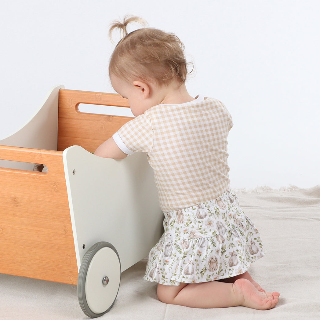 Baby wearing Organic cotton gingham bodysuit and cotton frill bunny skort playing with toys