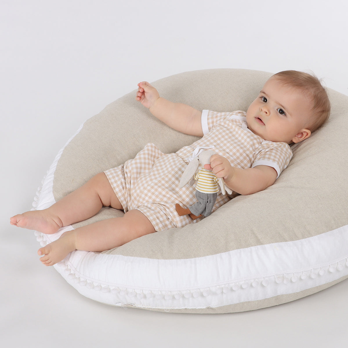 Baby playing on a lounger with ball wearing organic cotton shorts and bodysuit in gingham pattern and draw string 