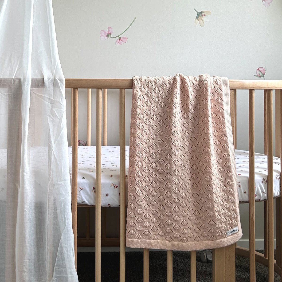 Merino peach knit blanket by Little Bee by Dimples draped over cot