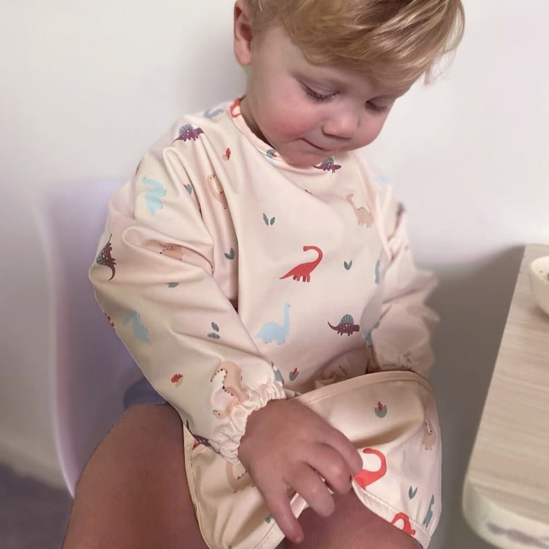 Baby boy wearing Waterproof long sleeve bib from Over the Dandelions in Dino print