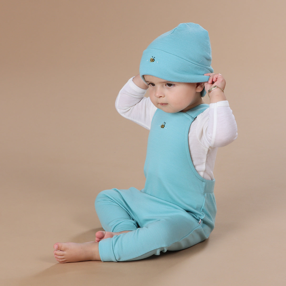 Baby wearing merino beanie with hand embroidery bee