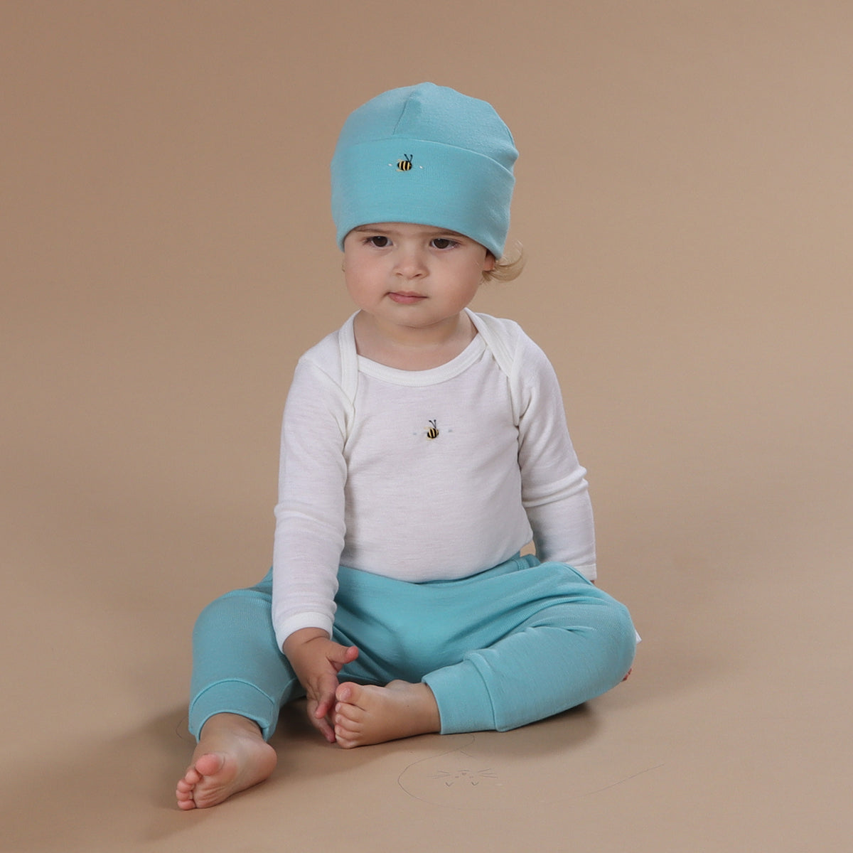 Baby wearing merino beanie with hand embroidery bee