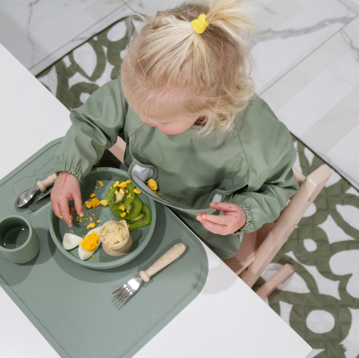 Baby on a highchair with quilted playmat from Zazi underneath