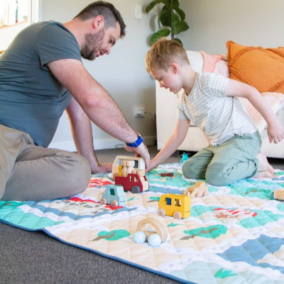 Father and boy playing on quilted playmat in tiny town print from Zazi
