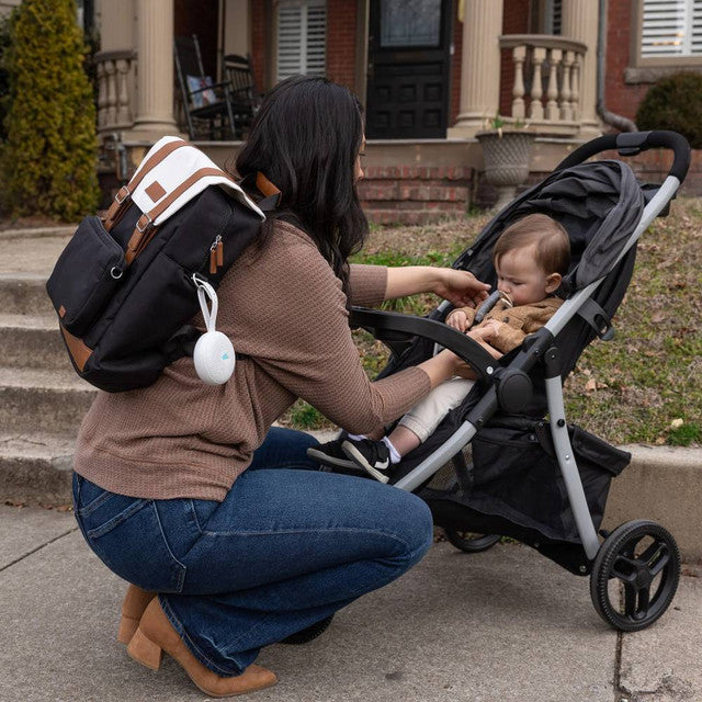 Mommy with kid in stroller outdoors with Yogasleep Hushh+ attached with a diaper bag