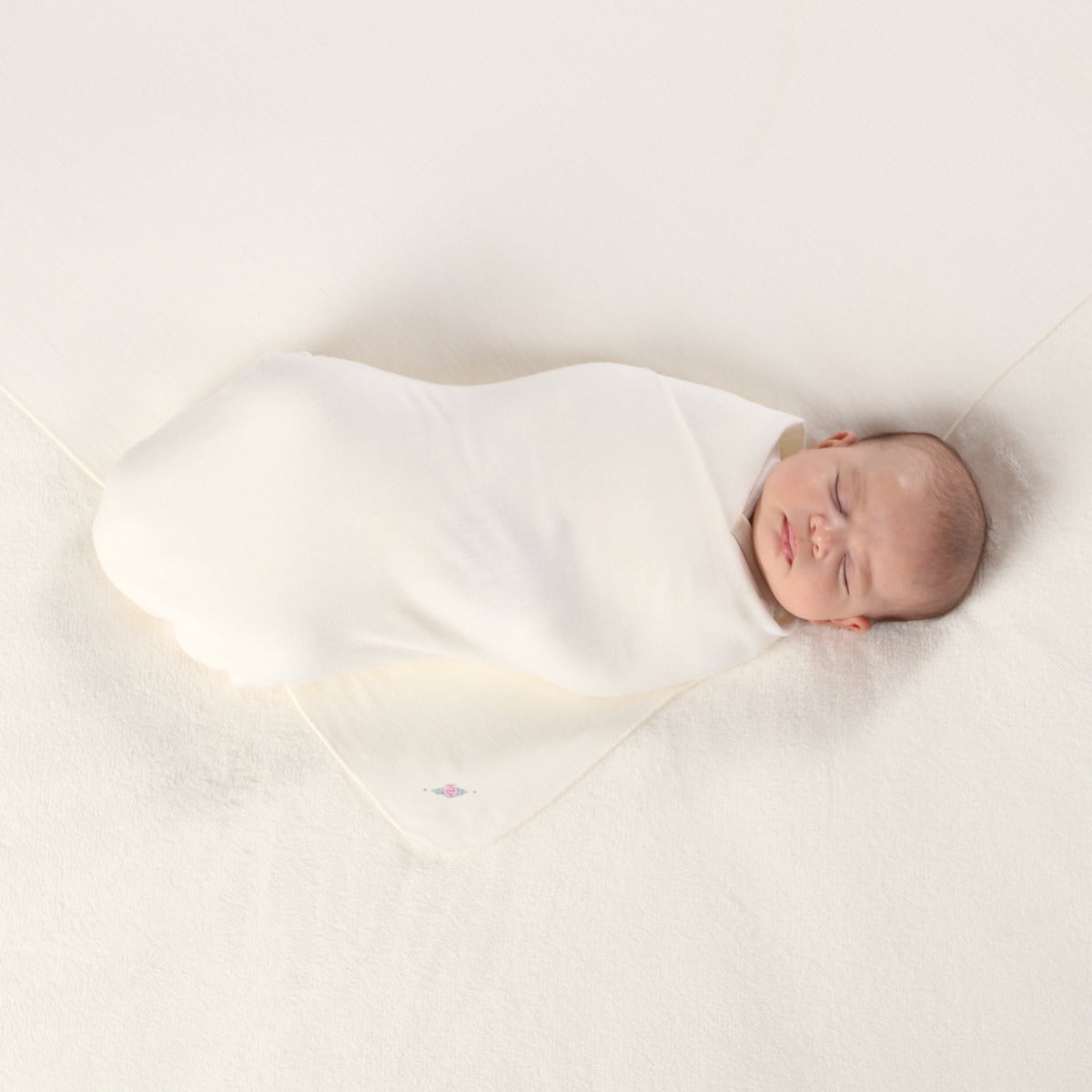 Dimples Classic merino swaddle in cream rose on sleeping baby 