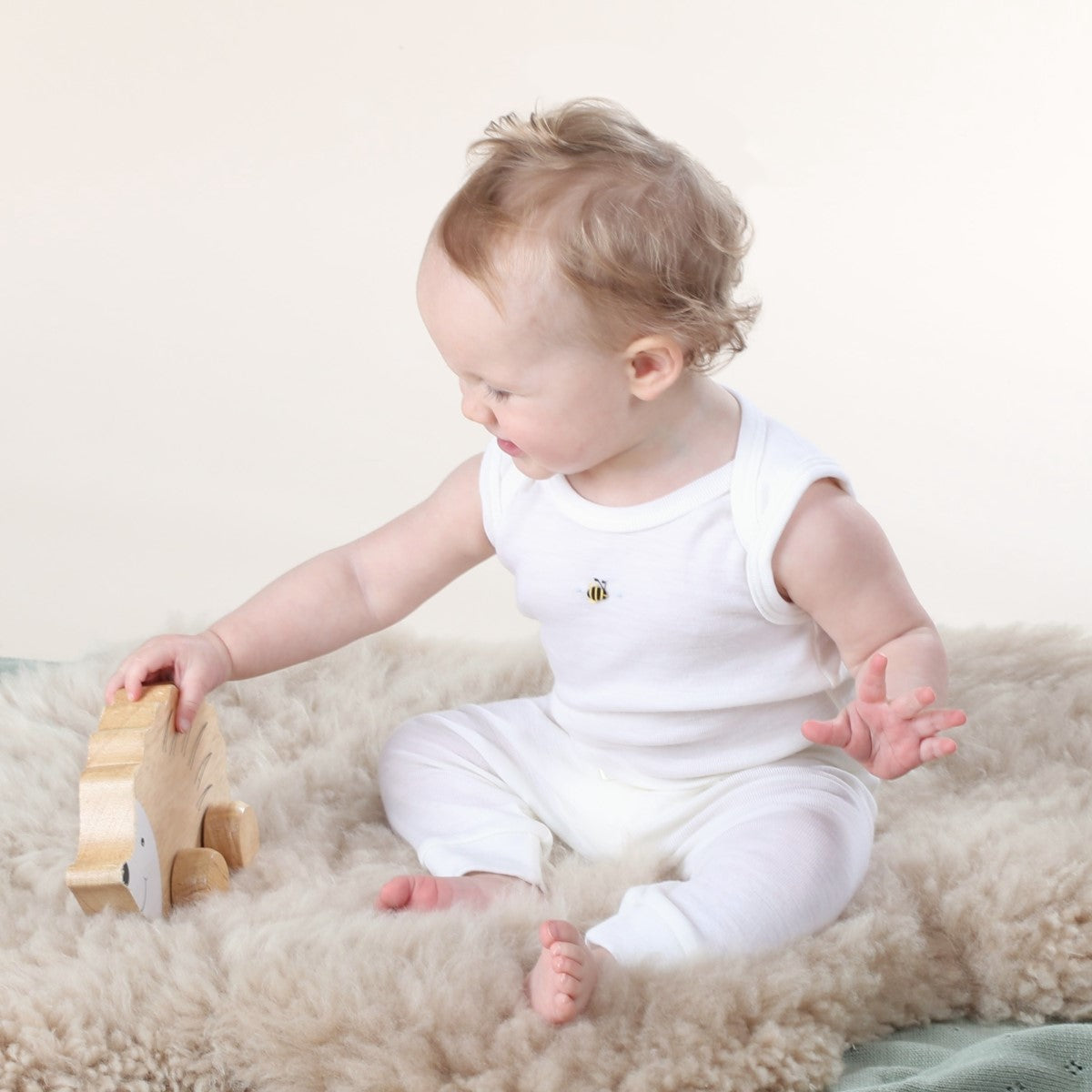 Dimples cream bee sleeveless bodysuit on baby playing