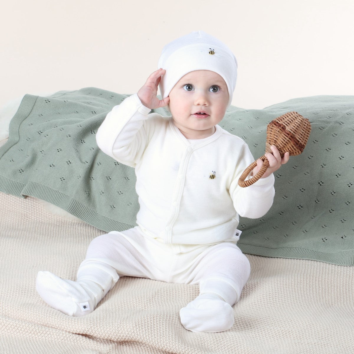 Dimples Cream bee merino cardigan on baby with toys