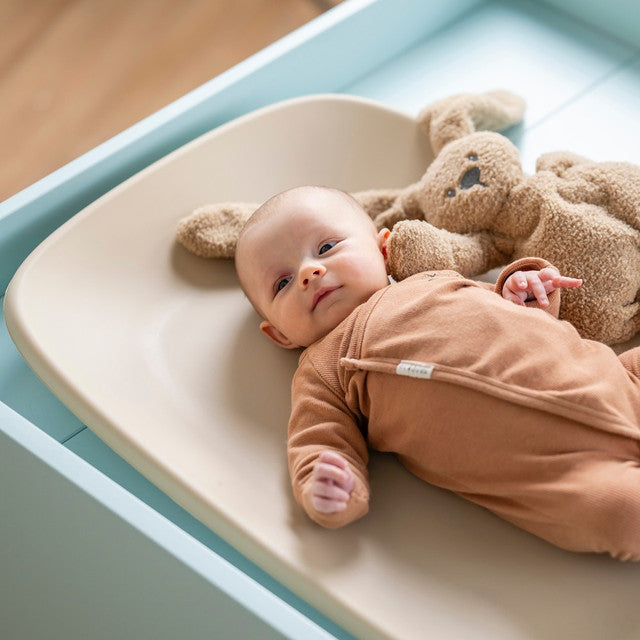 Baby on changing table in Baby Change Mat from Nattou in beige