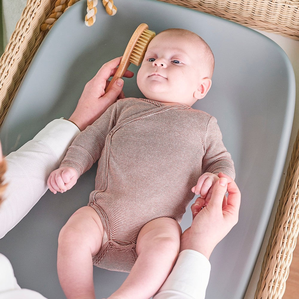Mother getting baby ready on Baby Change Mat from Nattou in grey