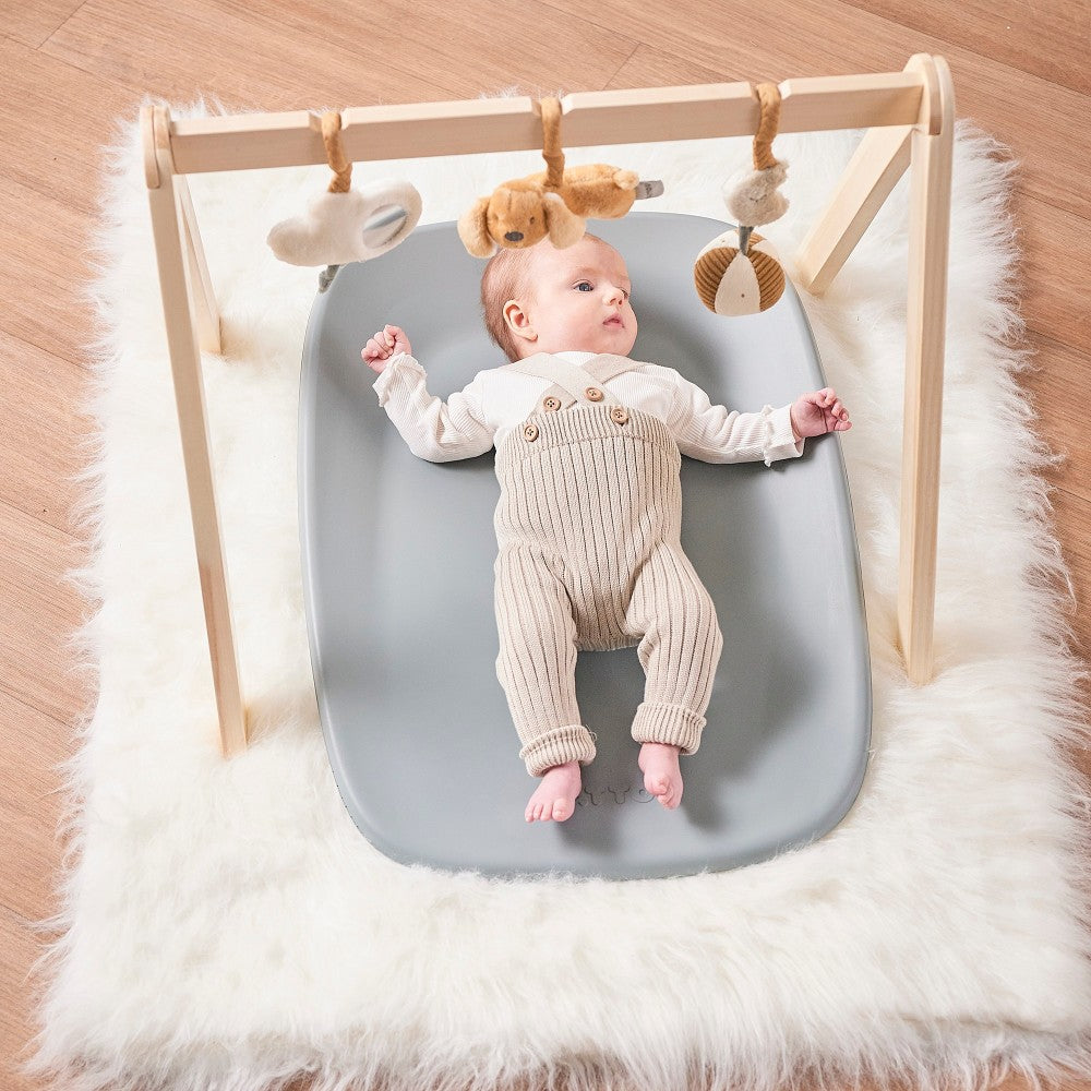 Baby playing with toys on Baby Change Mat from Nattou in grey