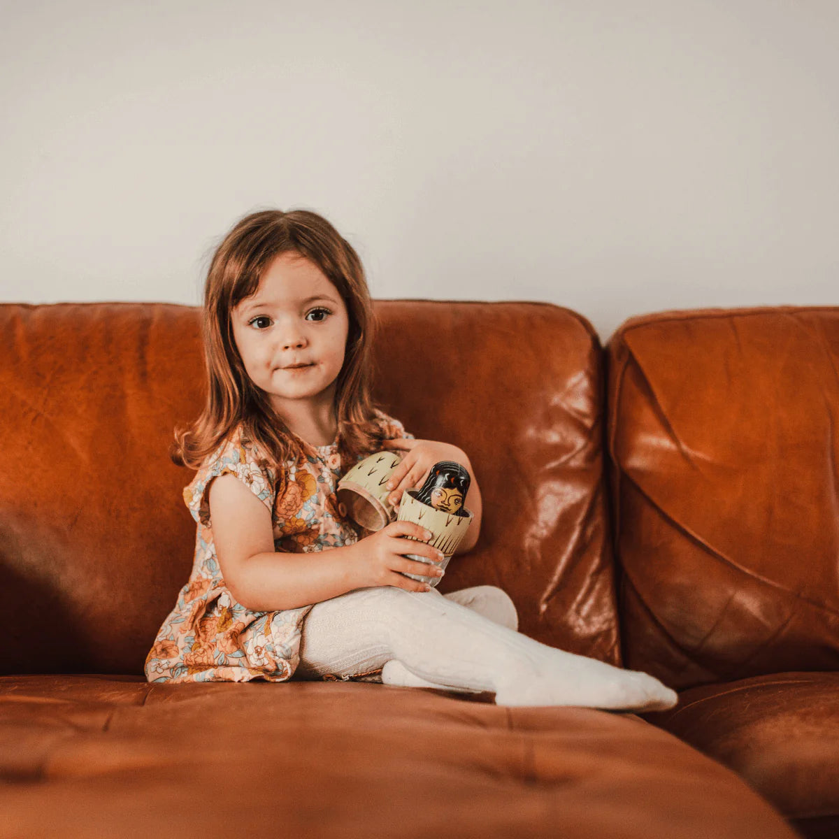 Girl wearing Natural Baby and Child Merino Wool Knit Cable Tights from Lamington sitting on a sofa