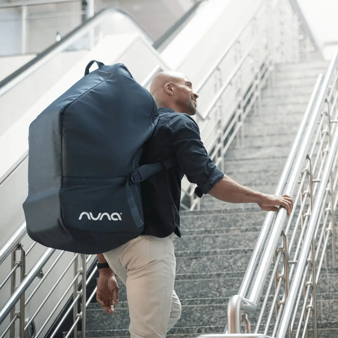 Man on stairs with Nuna Pipa Travel Bag in indigo on back