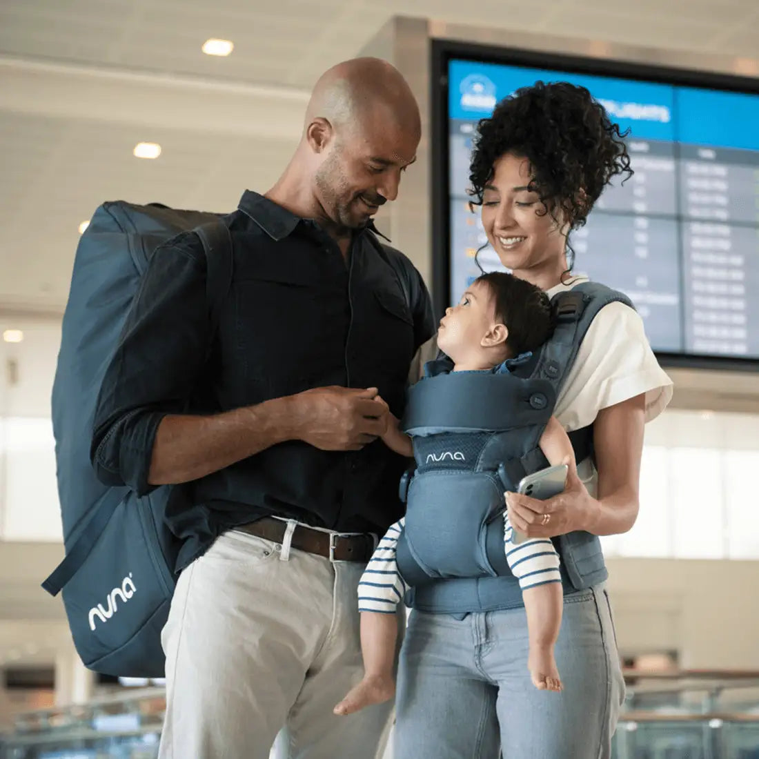 Parents wth baby carrying Nuna Pipa Travel Bag in indigo and Baby in carrier